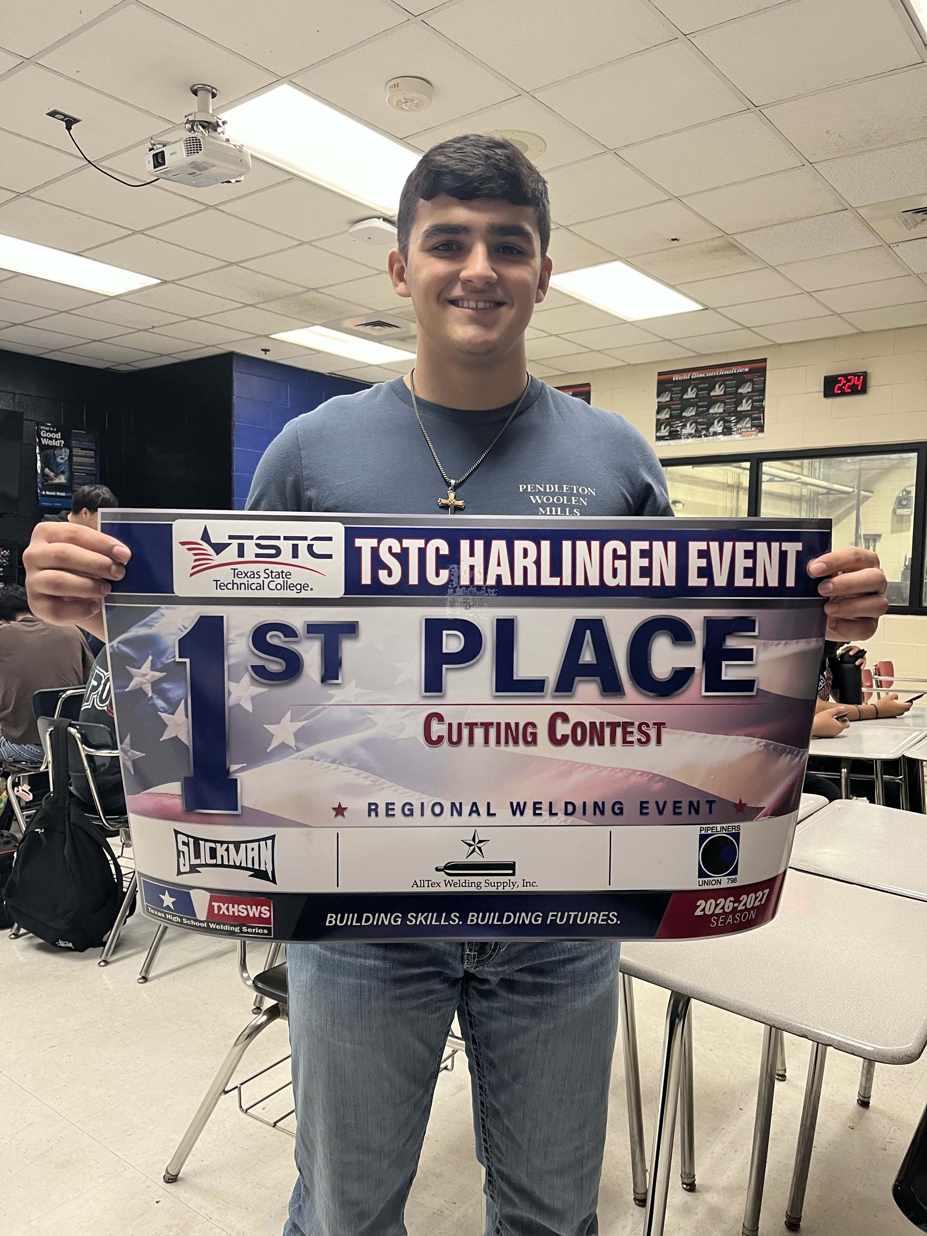 A young man proudly holds a large banner that reads "1ST PLACE Cutting Contest" at a regional welding event.