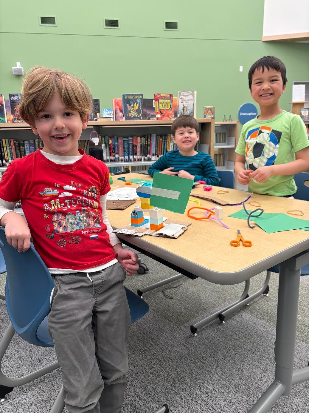 Kindergarten students work on engineering activities with cardboard, construction paper and masking tape.