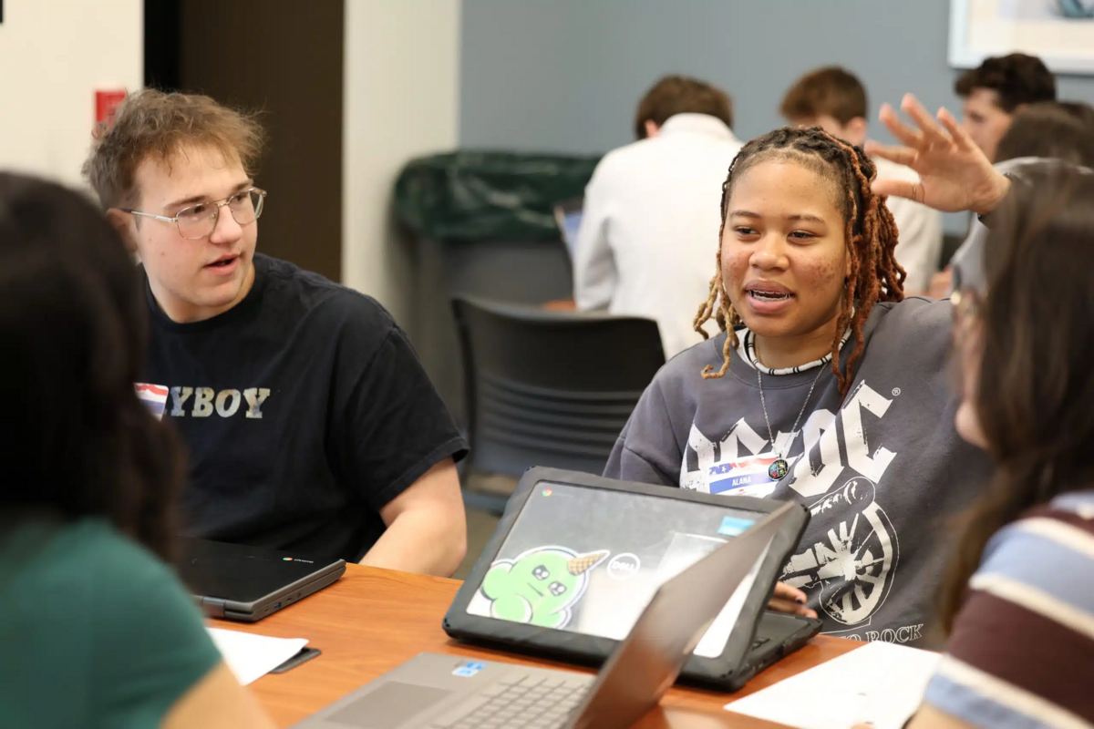 A high school student raising her hand in a meeting.