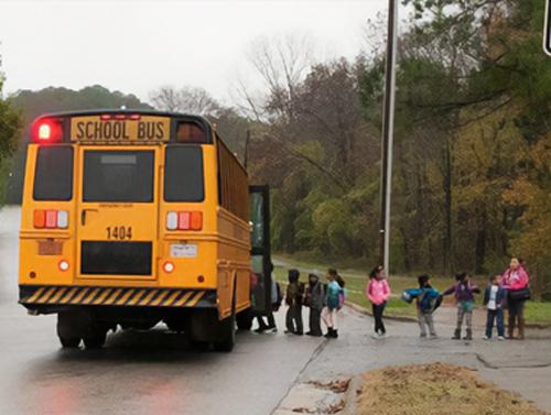 Children lined up to enter a yellow school bus