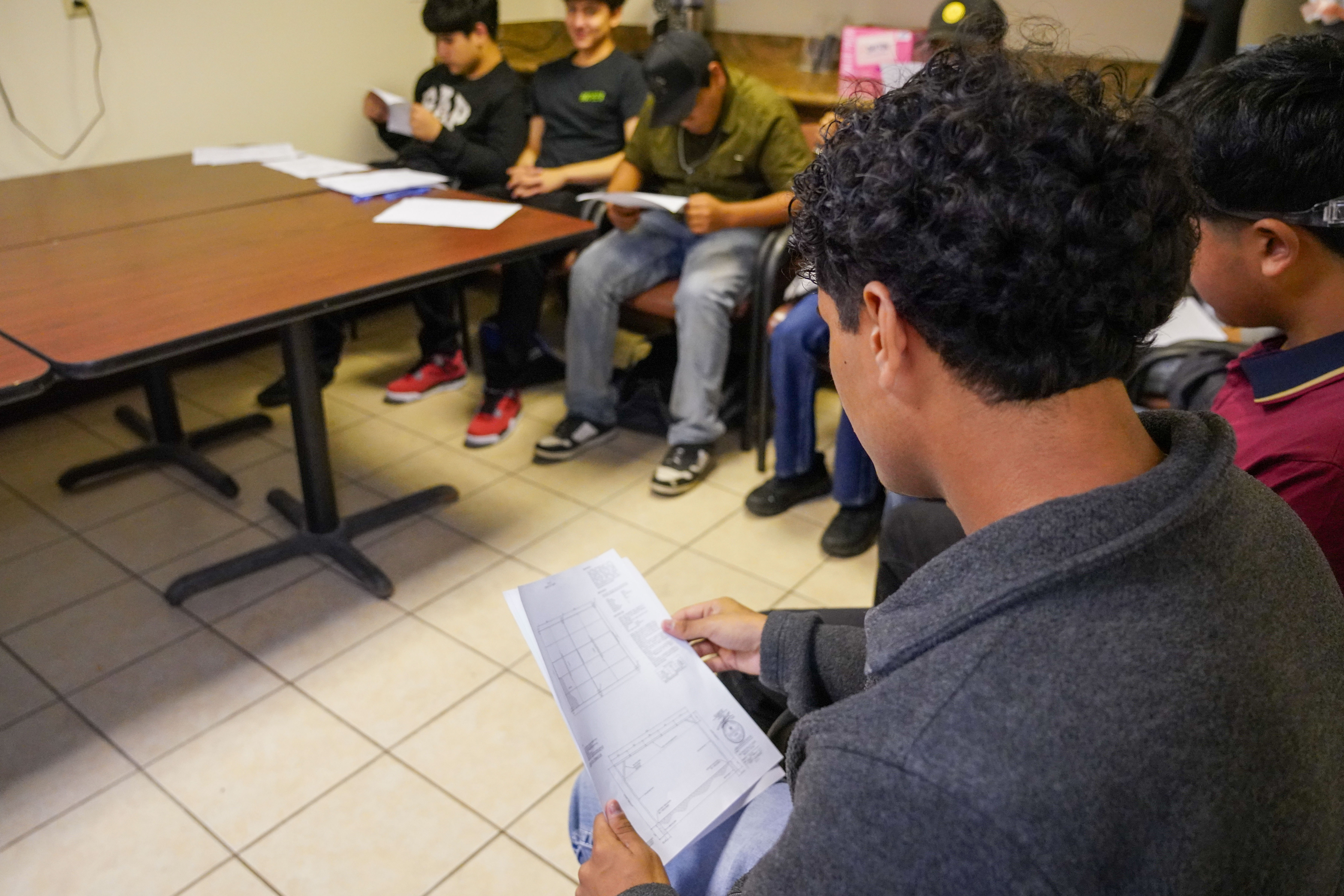 Several young men sit around a table, each holding and reviewing documents.