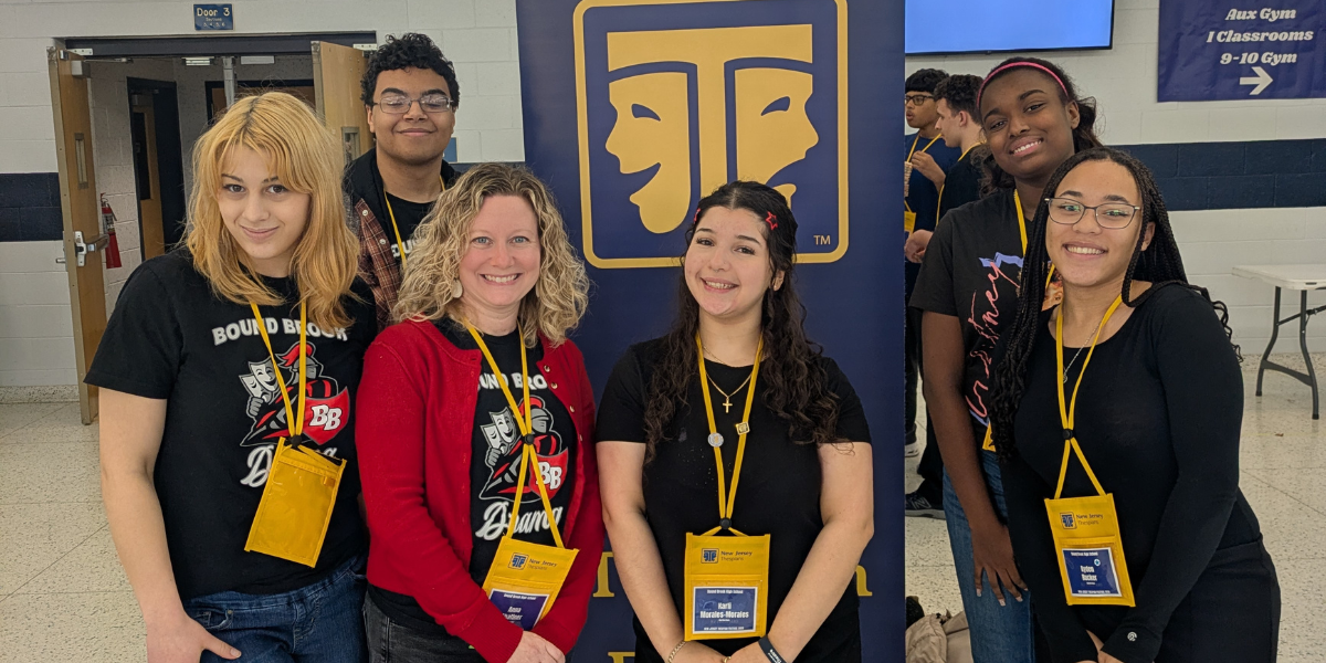 A photo of students and teacher at the entrance of the Thespian Festival wearing lanyards with badges.