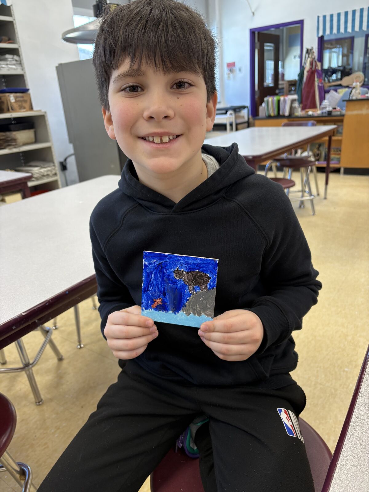 A young student holds a small painting.