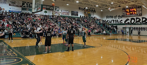 A basketball game is underway in a crowded gymnasium with spectators in the stands.