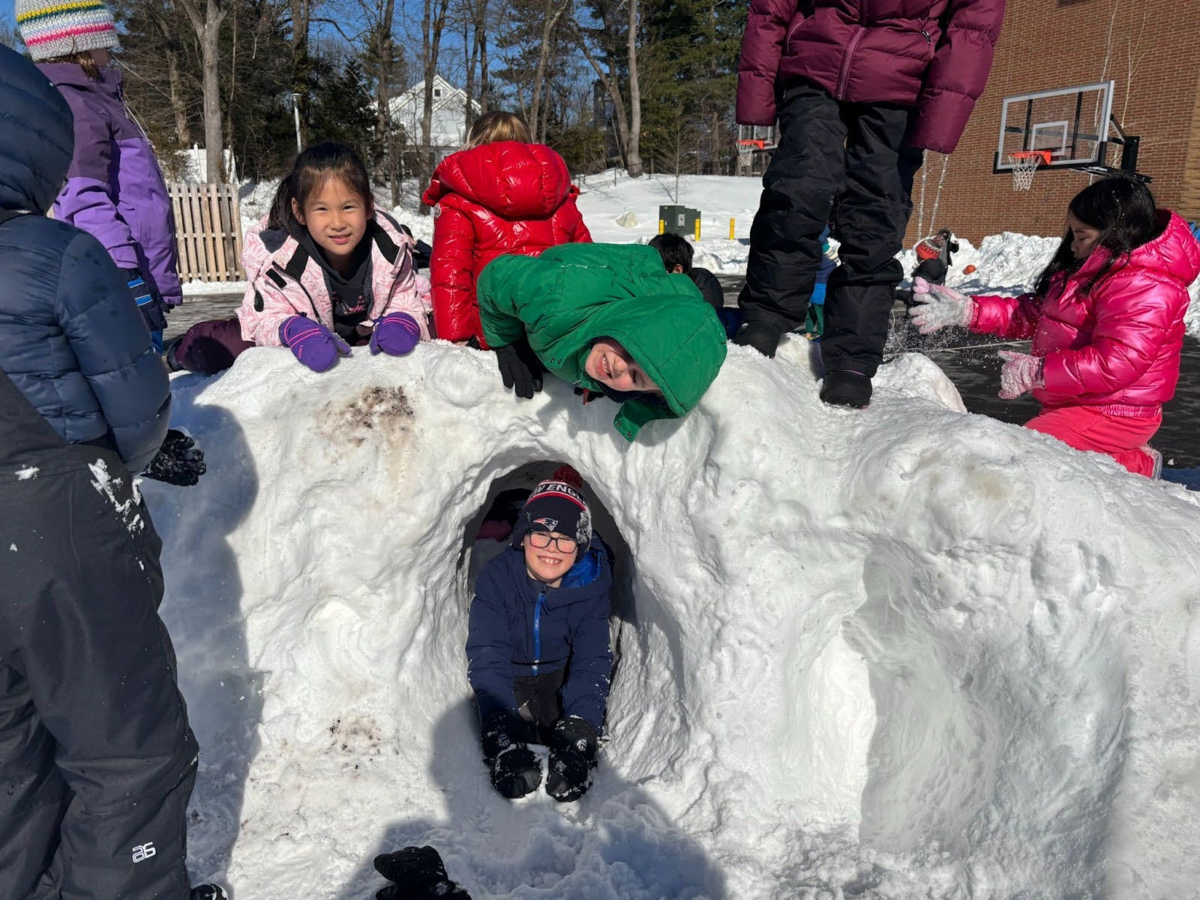 Students build a fort in the snow at recess.