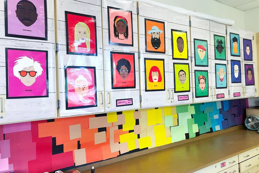 A wall of colorful portraits of famous artists and figures, displayed in a classroom or studio.