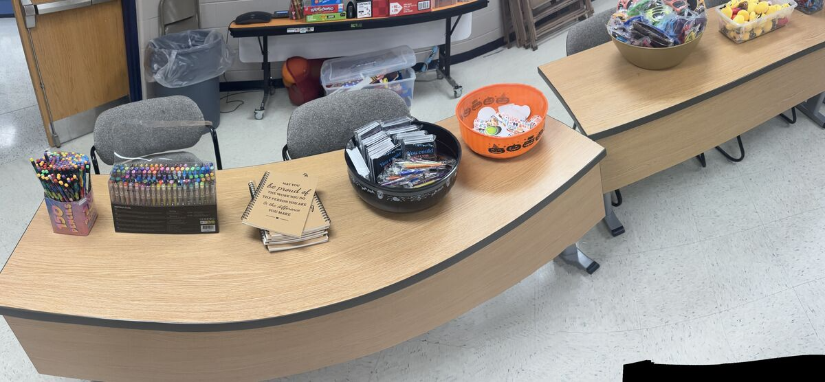 A desk is organized with colorful pens, pencils, notebooks, and small gifts in bowls.