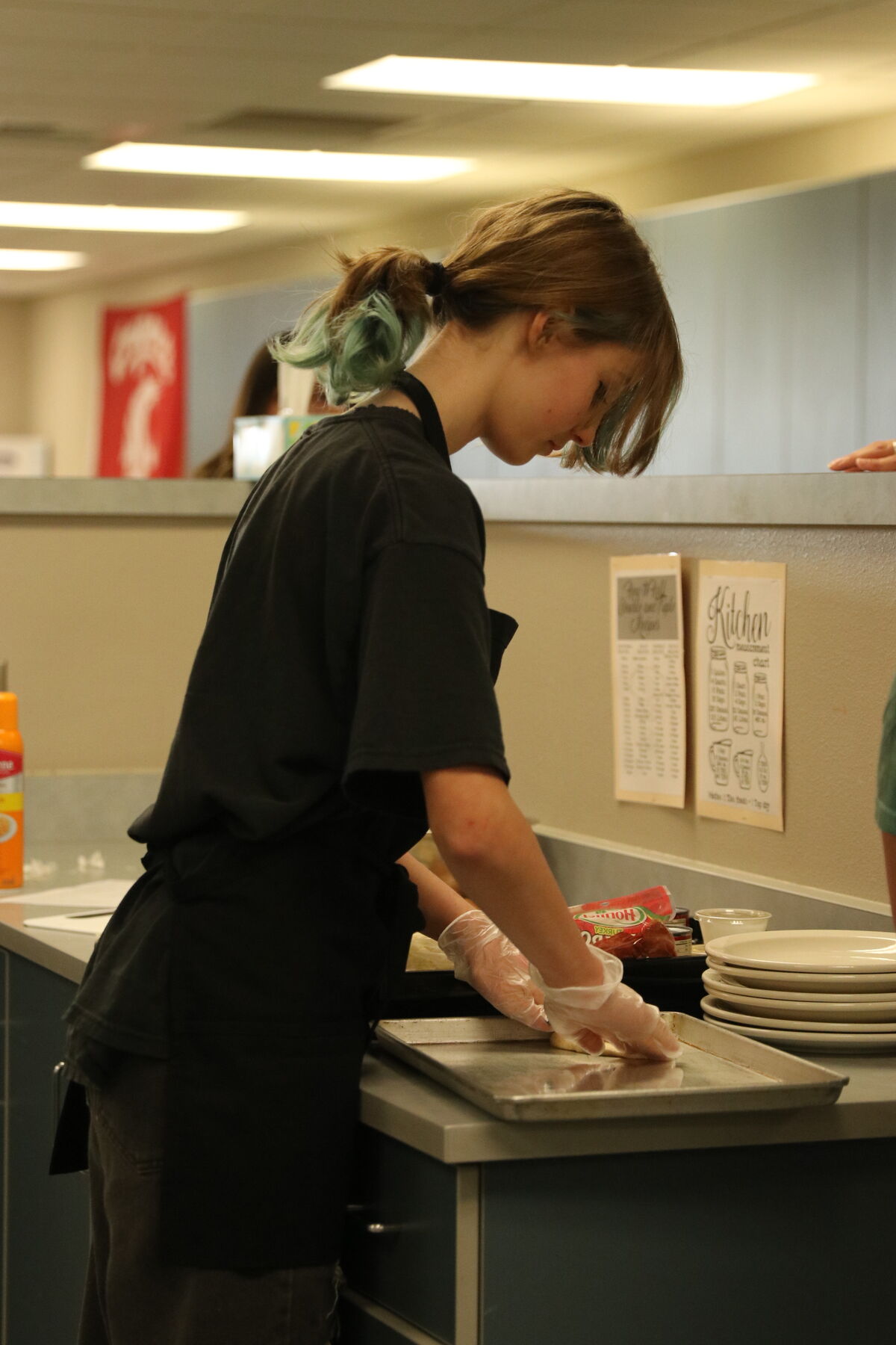 A person wearing gloves prepares food in a kitchen setting.