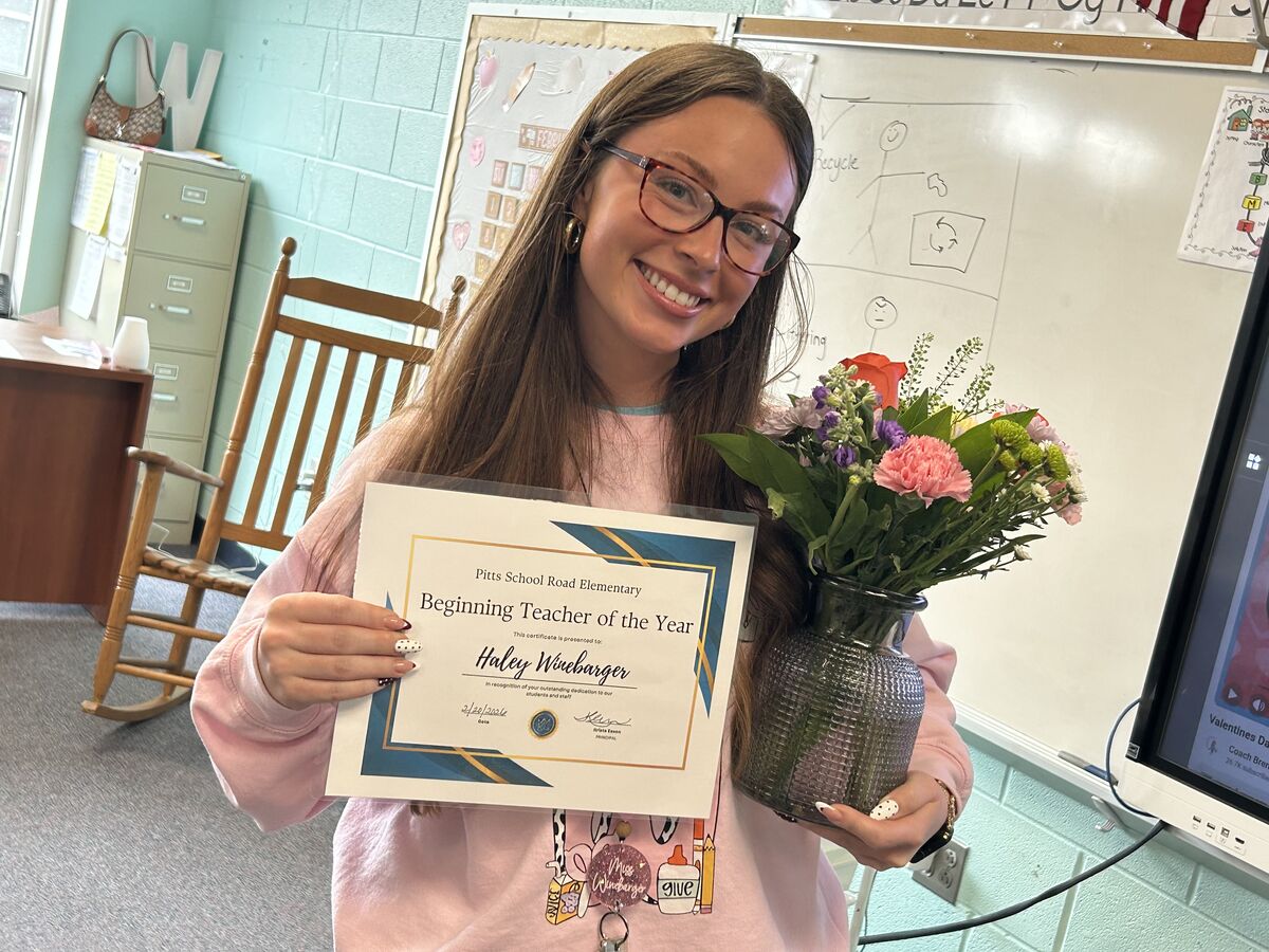 teacher holding a certificate and flowers