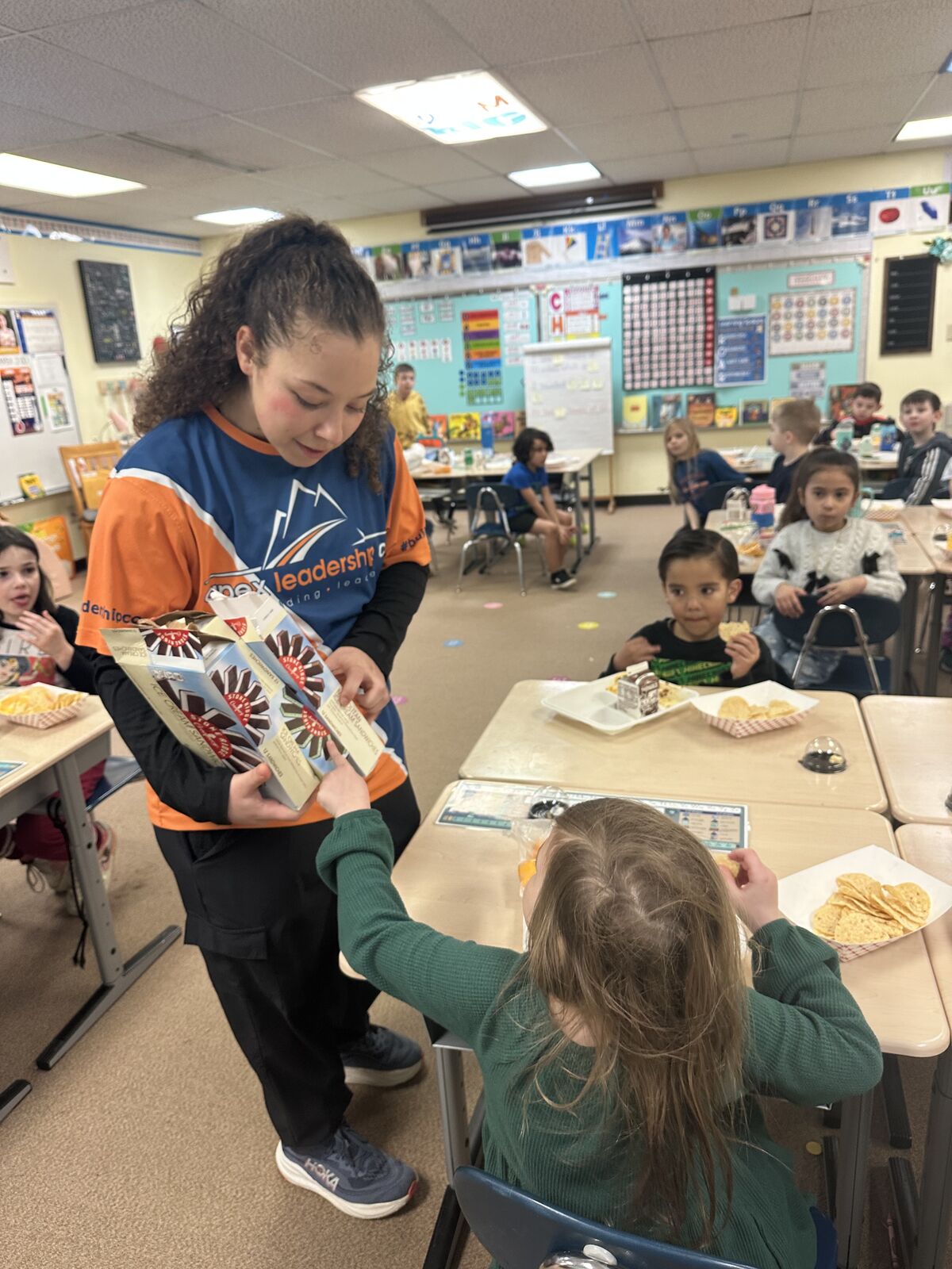 Students in a classroom are sharing boxes of ice cream sandwiches.