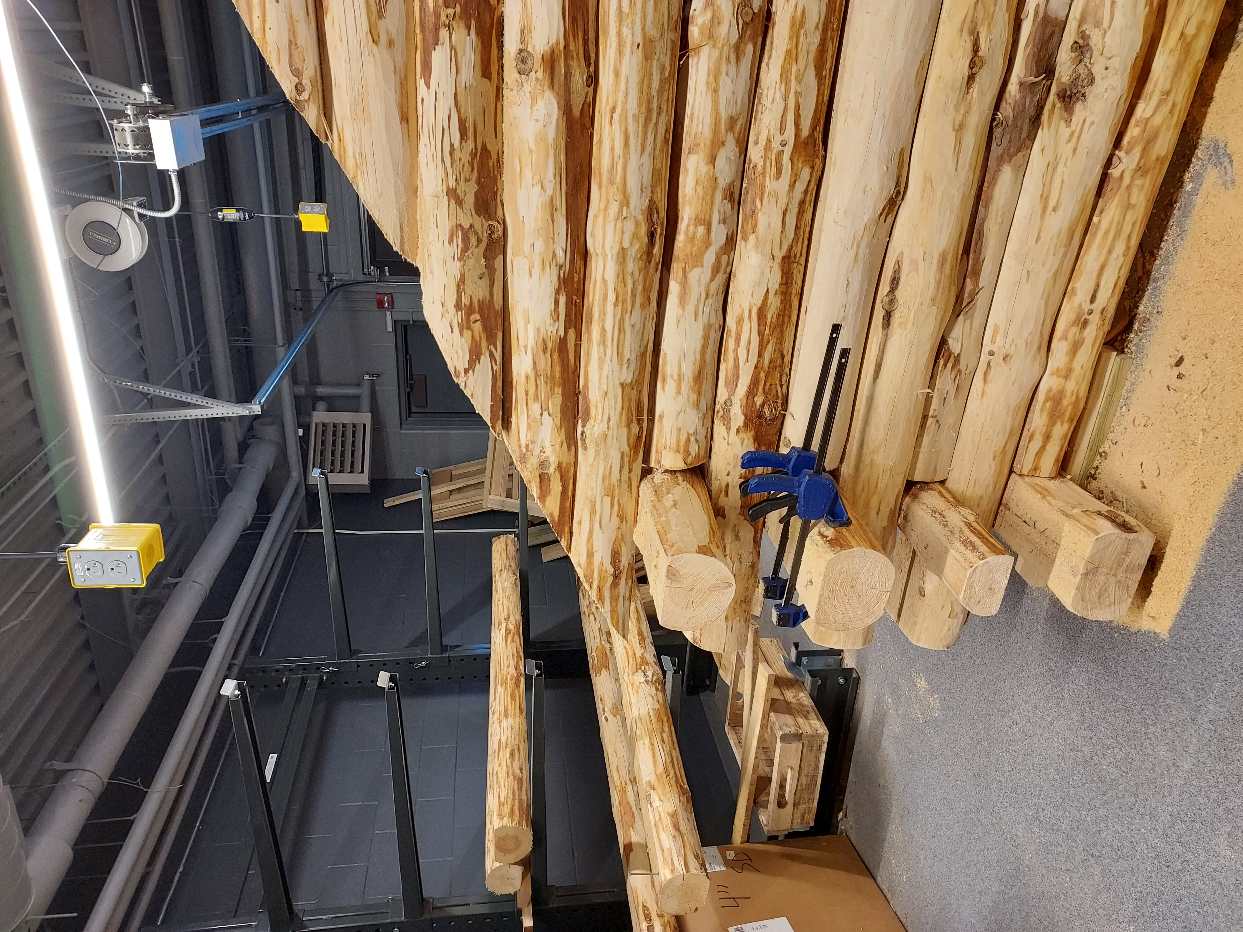 A construction project features unfinished wooden logs being clamped together.