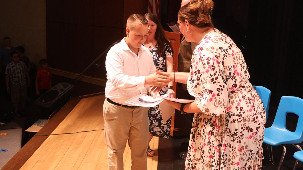 A student receives a certificate from Mrs. Mitchell