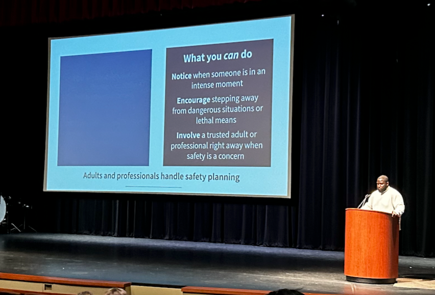 A speaker presents safety planning advice on a large screen in an auditorium.