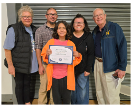 A young person proudly holds a certificate, surrounded by four smiling adults.