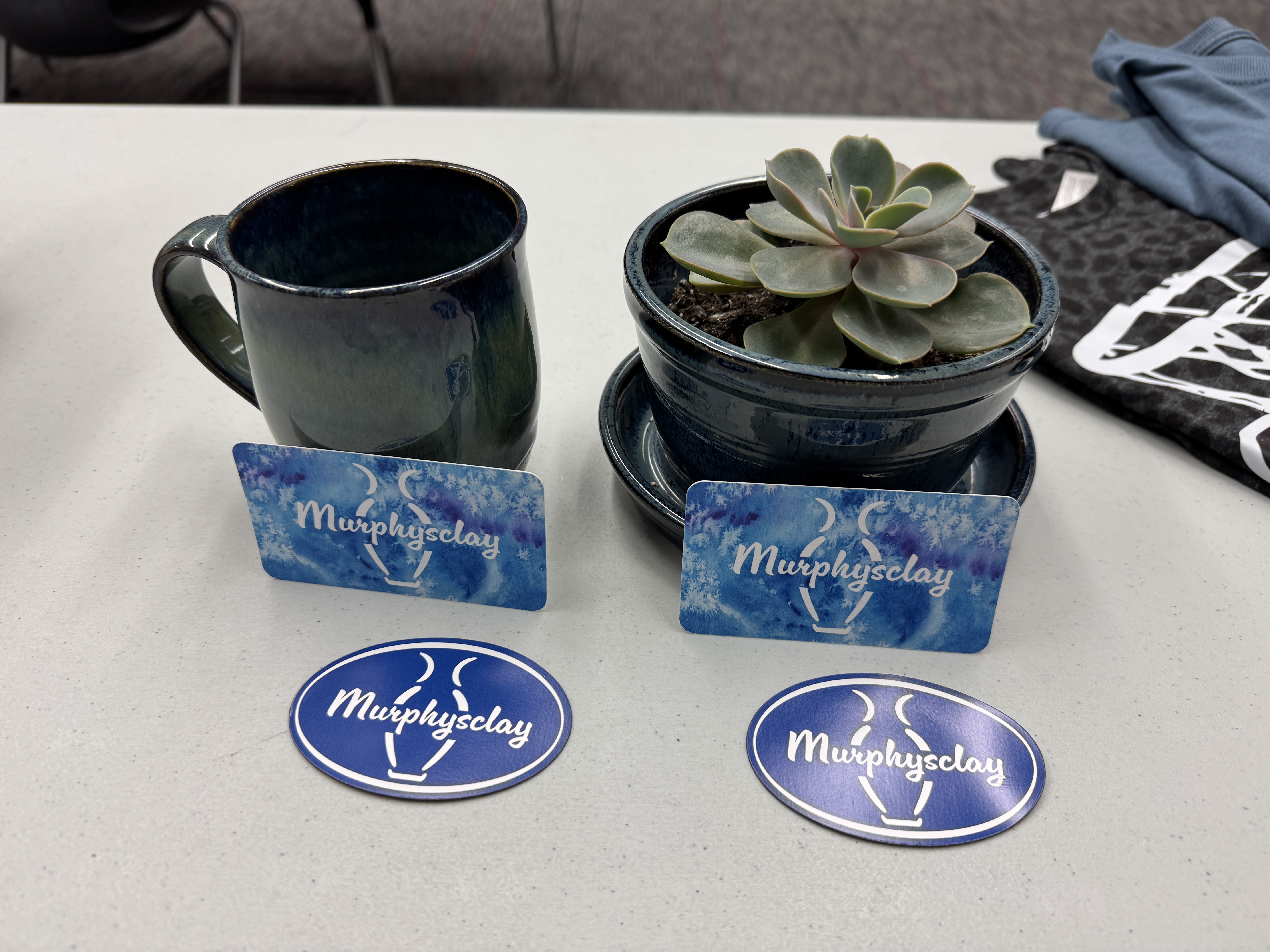 A dark blue ceramic mug sits next to a potted succulent on a table.