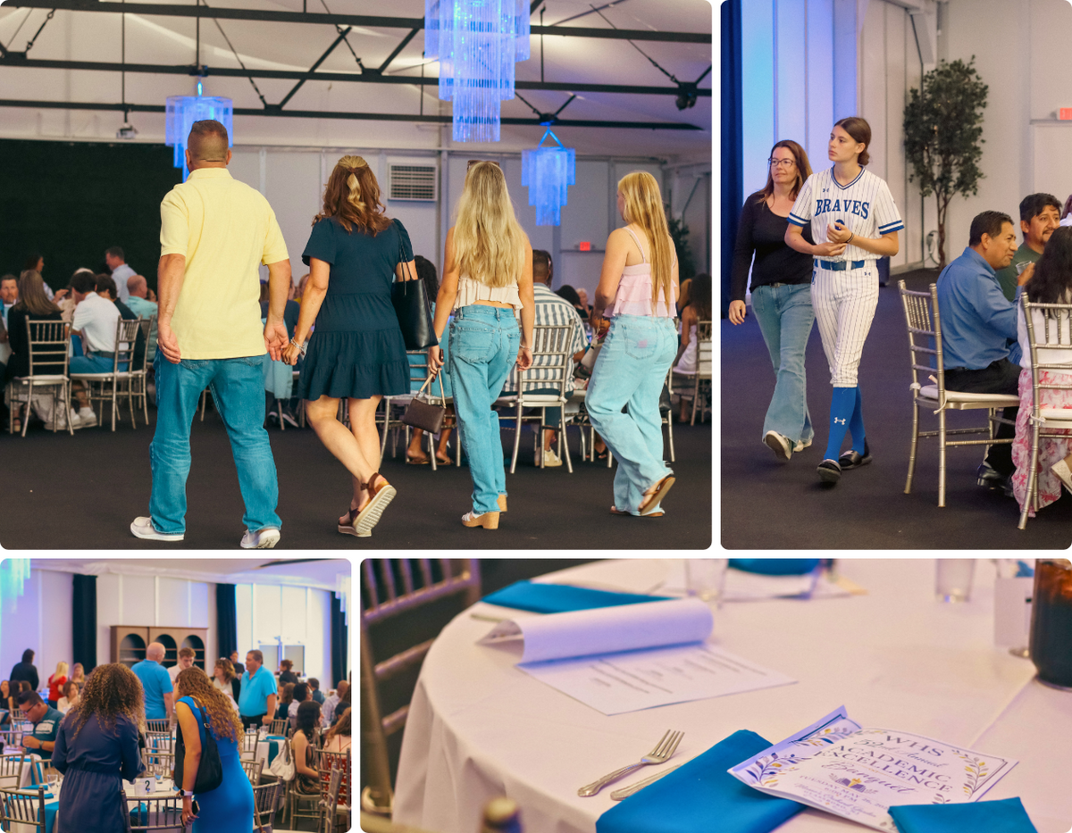 People walk through a banquet hall with blue chandeliers and seated guests.
