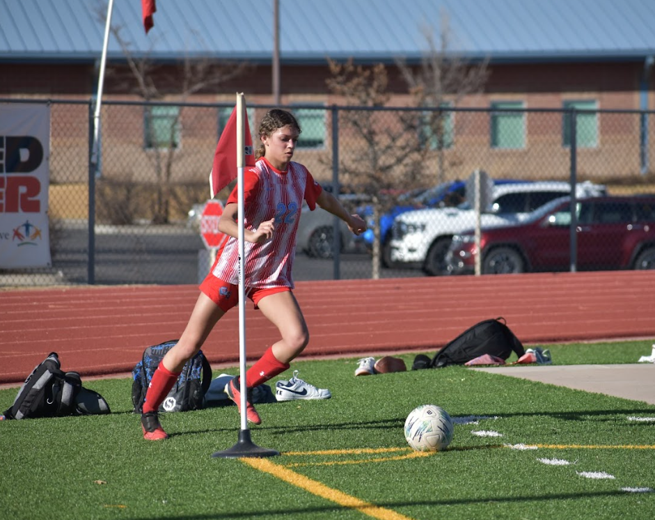 Kya kicks the ball back into bounds during a soccer game against Estes Park.