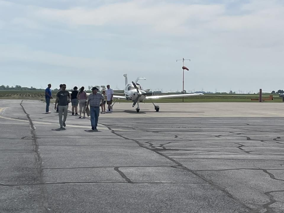 A group of people walk on an airport tarmac towards a small airplane.