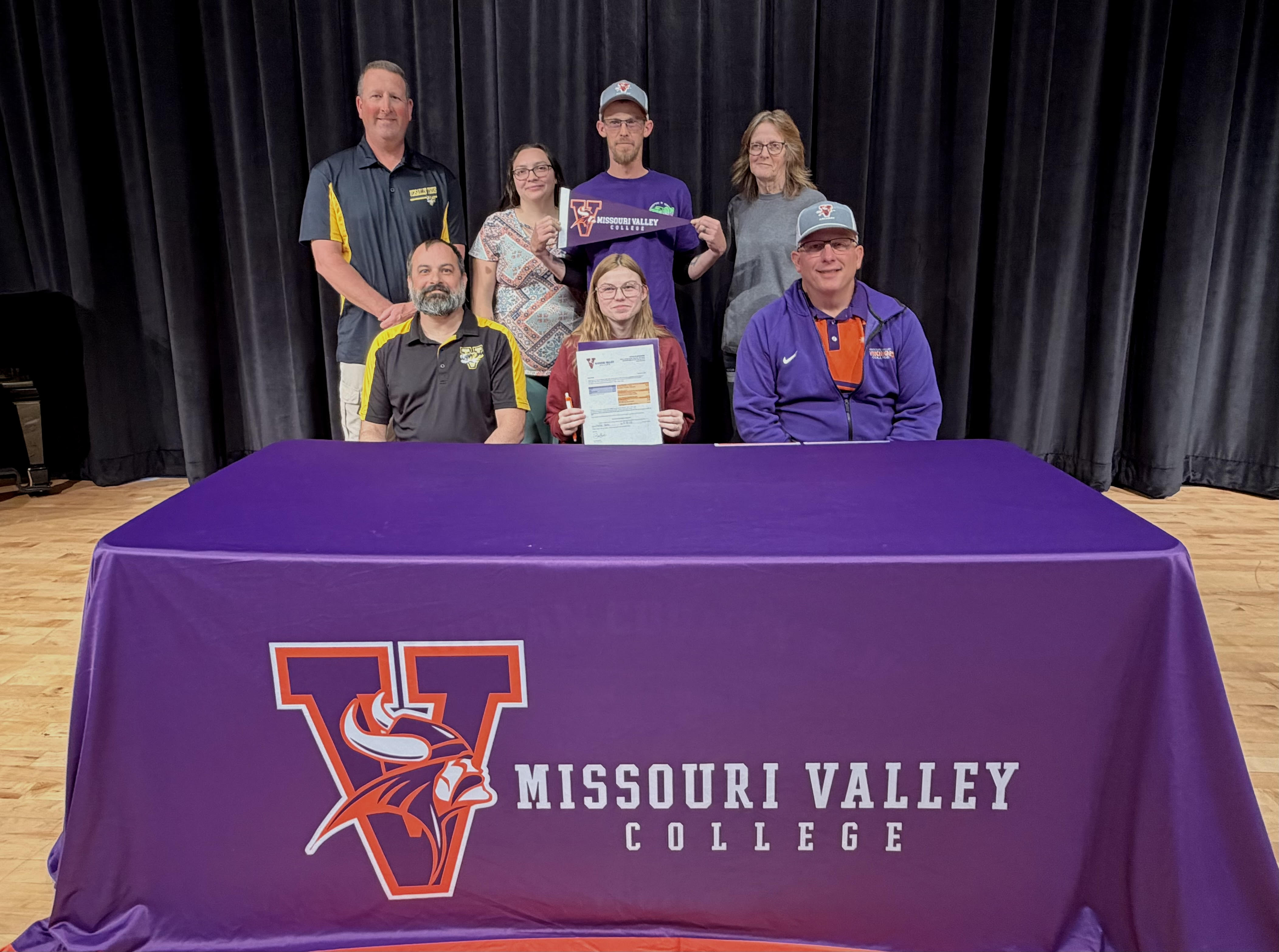 A group of people, some wearing Missouri Valley College apparel, pose for a photo for a college signing for archery.