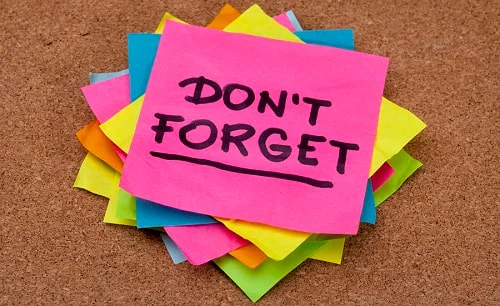 A stack of colorful sticky notes on a corkboard, with the top pink note reading 'DON'T FORGET'.