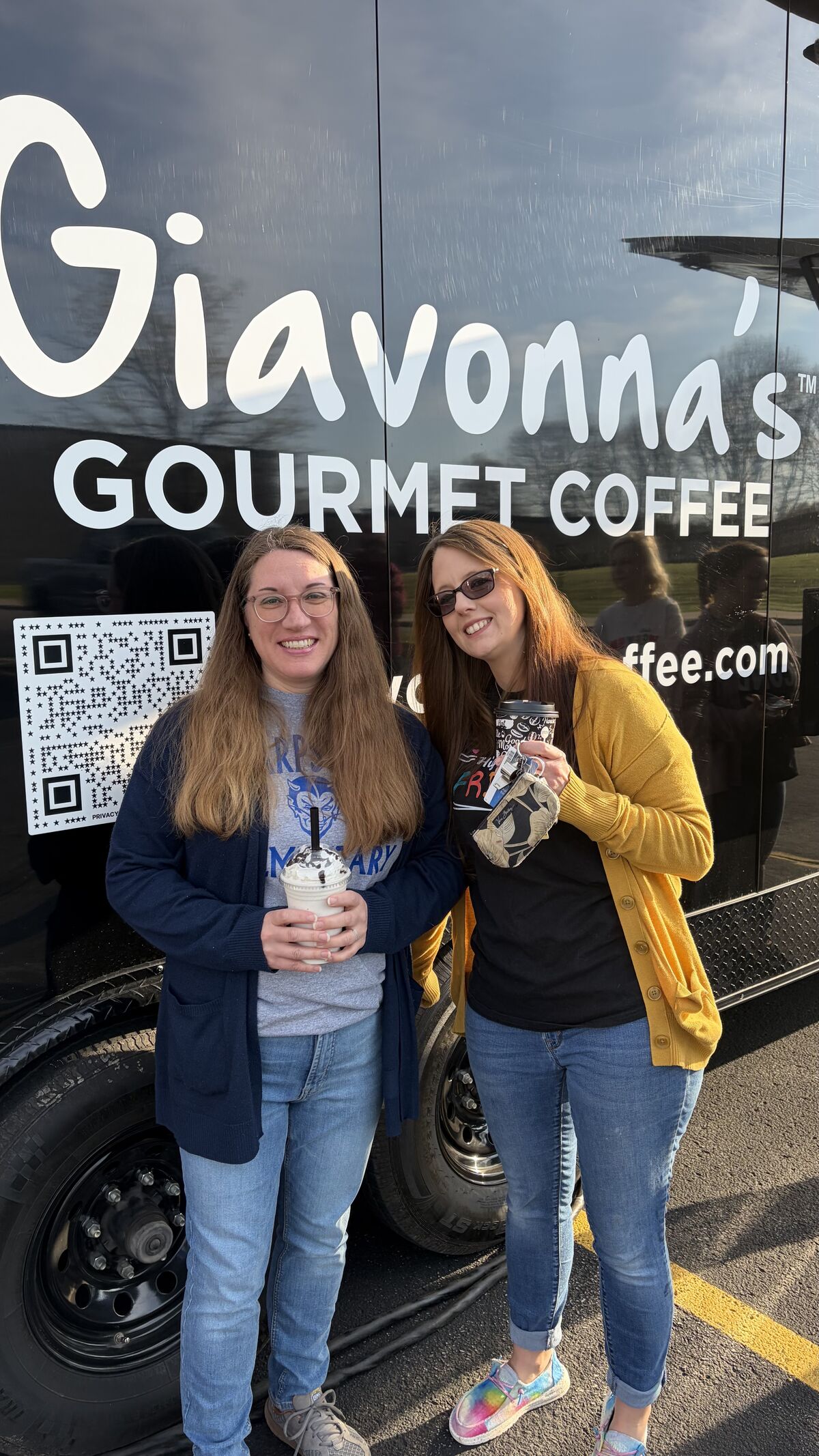 Two smiling women stand in front of a black coffee truck with "Giavonna's GOURMET COFFEE" written on the side.