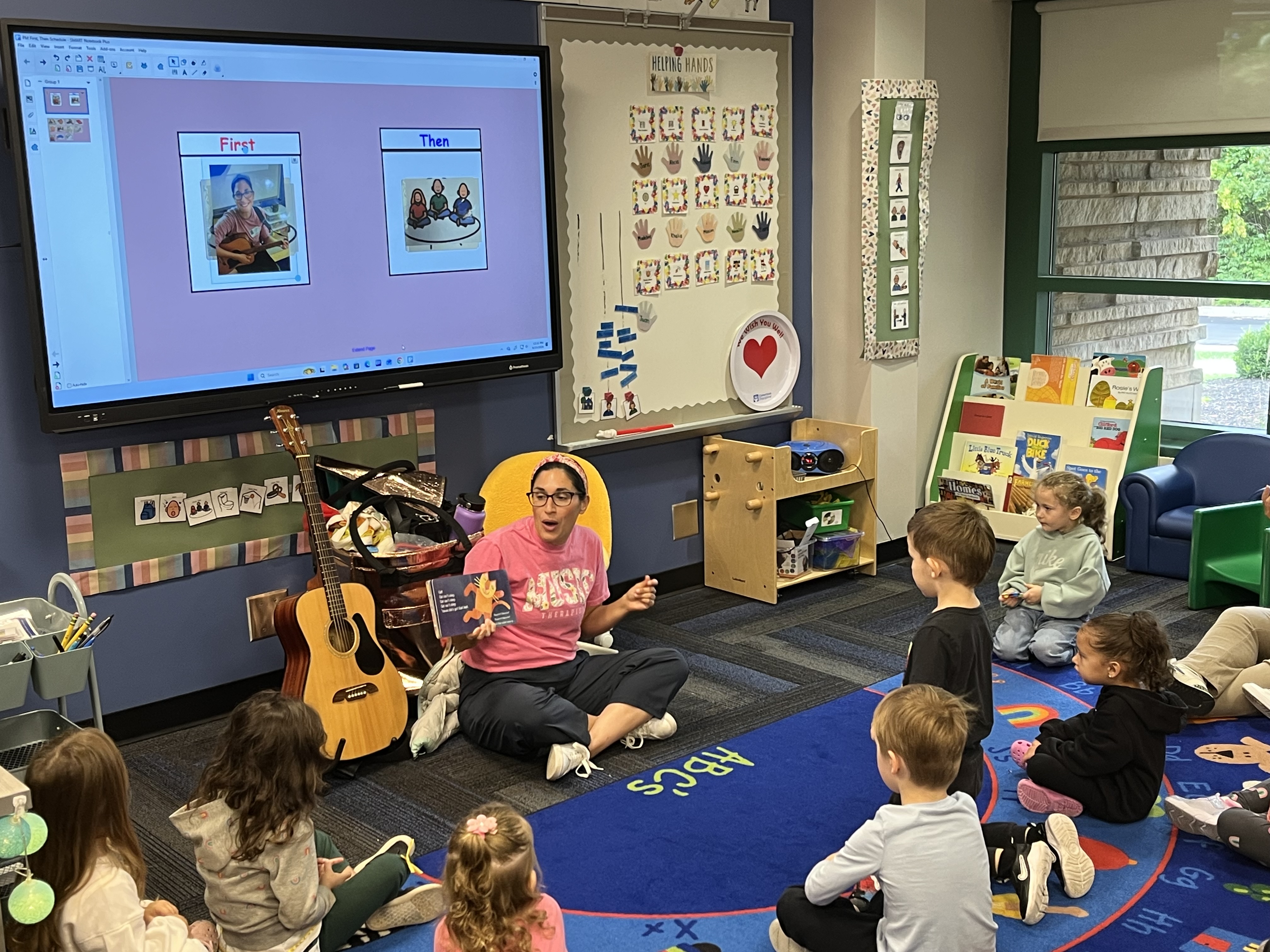 Miss Abbey reads to students who are seated on the carpet