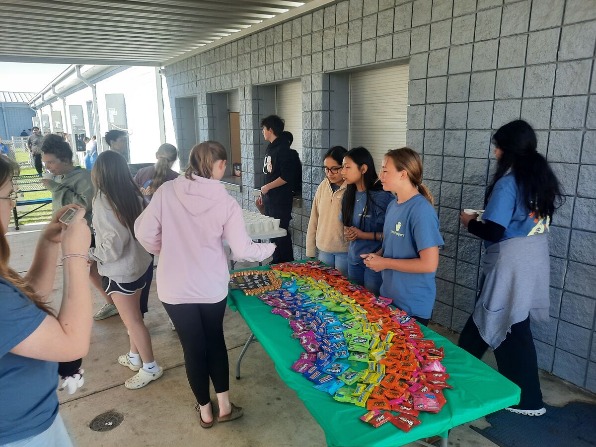 Students gather around a table displaying a colorful array of candy, arranged like a rainbow.