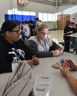Achieve Academy students playing UNO at a cafeteria table.
