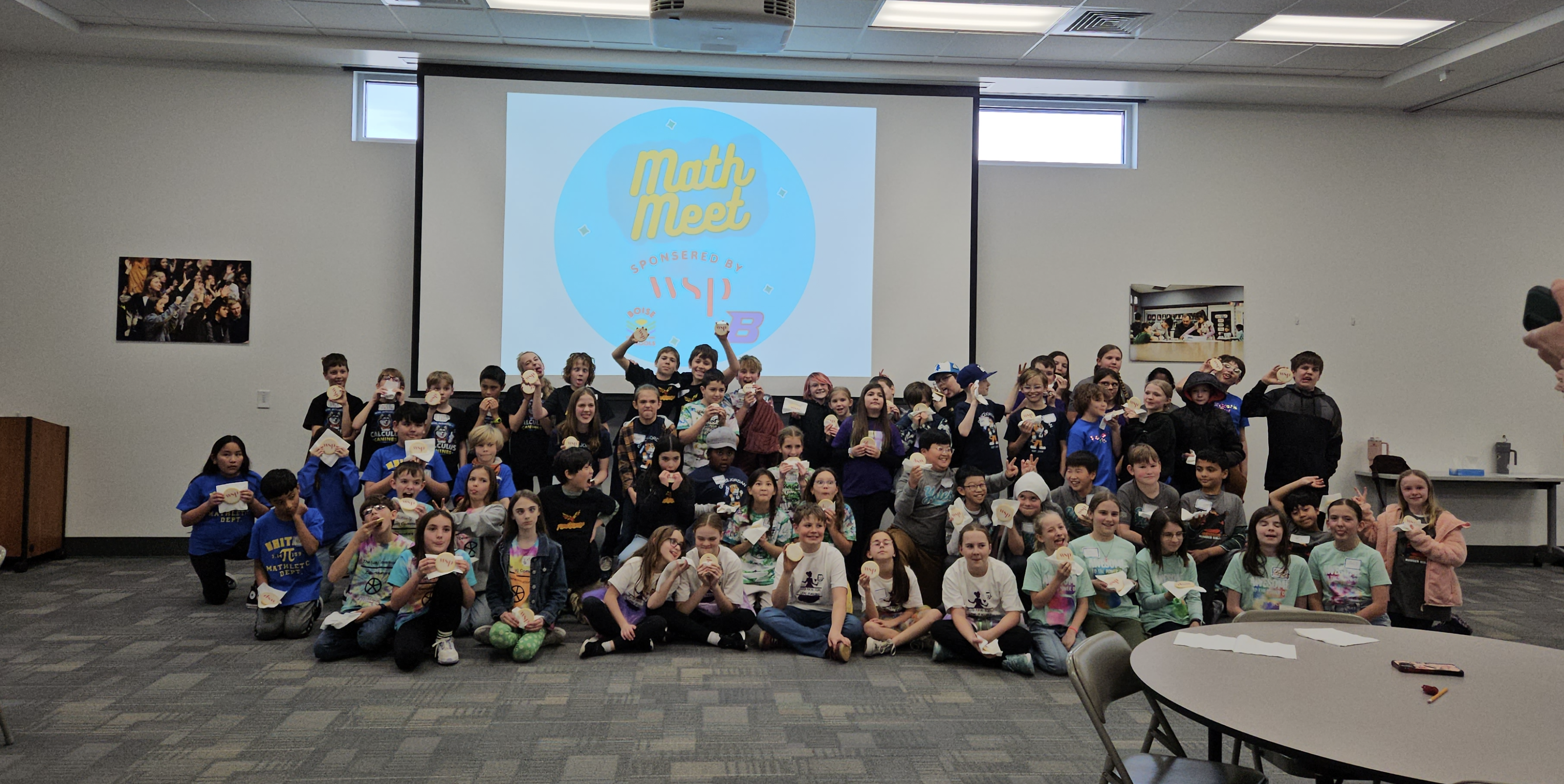 A large group of students pose for a photo in front of a projector screen displaying 'Math Meet' and 'Sponsored by WSP'.