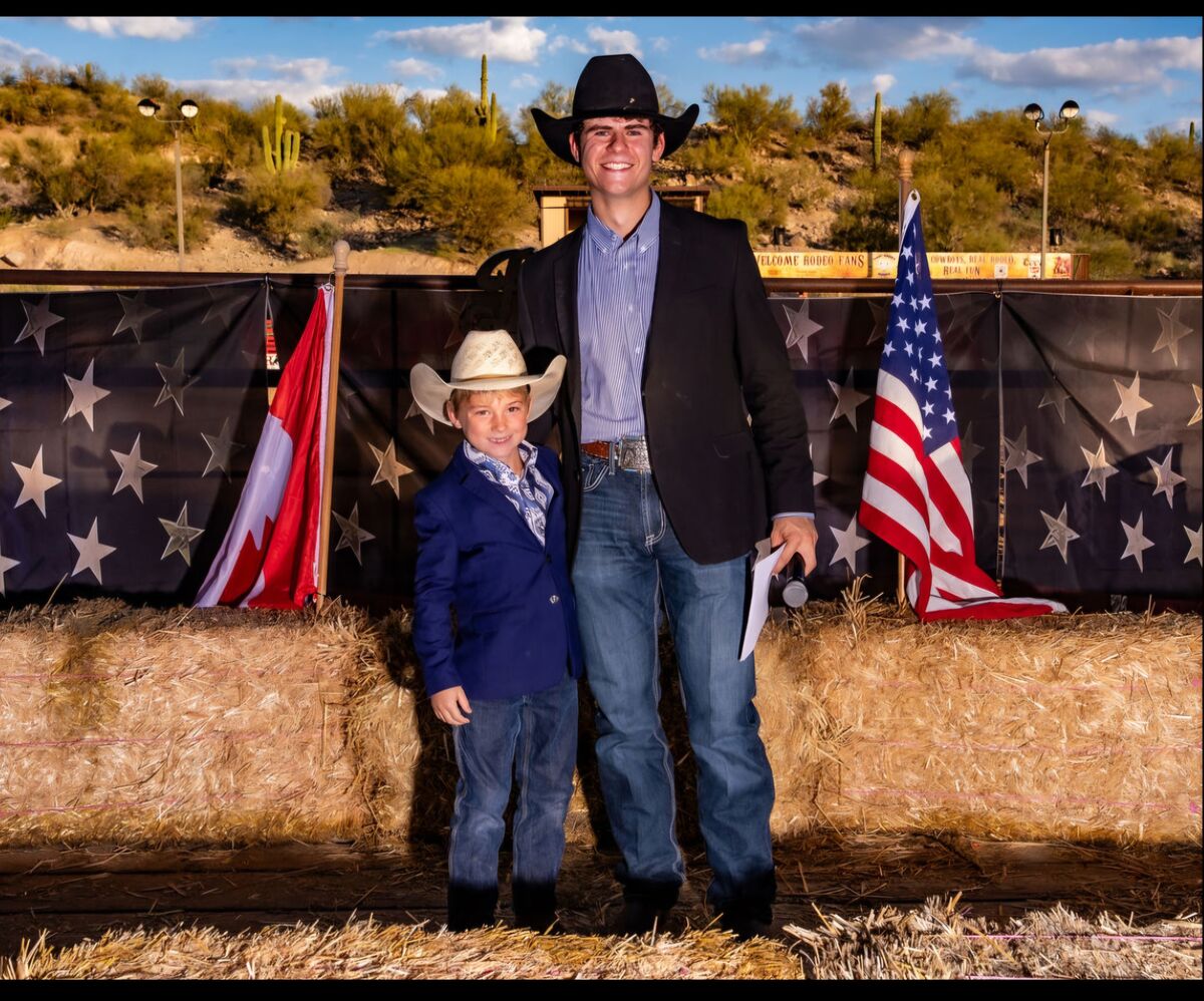 Charles Brock in jacket and cowboy hat posing with an adult in similar attire
