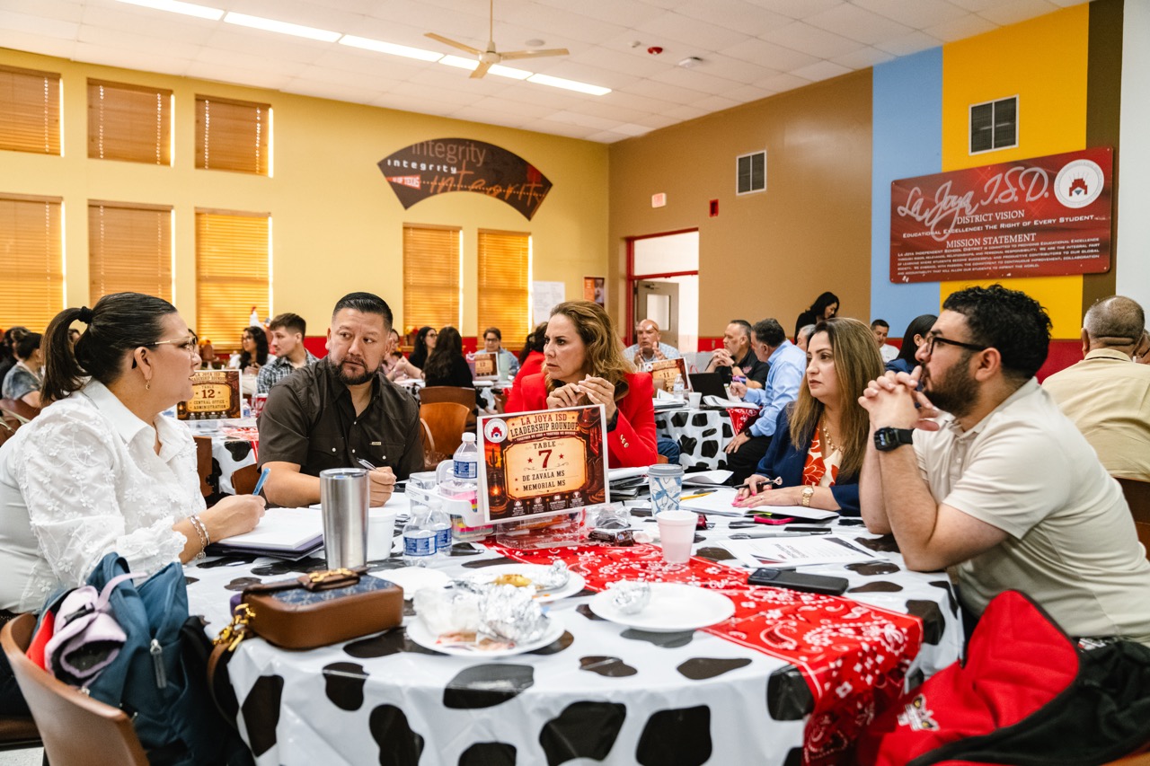 People seated at tables in a conference room, engaged in discussion during a La Joya ISD Leadership Roundup.