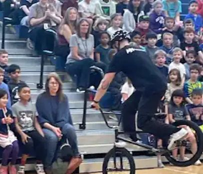 BMXer does a trick in front of grade 1 students