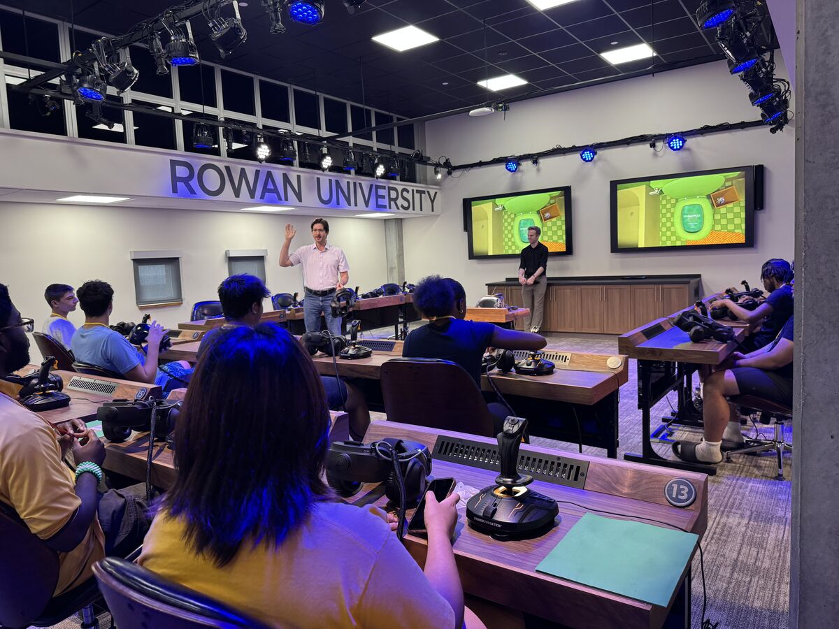 Students at Rowan University engage with VR equipment and joysticks in a classroom setting.