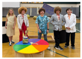 Five children in 1970s-inspired disco outfits pose around a colorful disco ball prop.