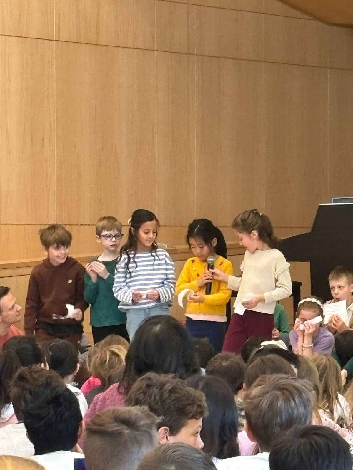 Students speak into microphone during assembly. 
