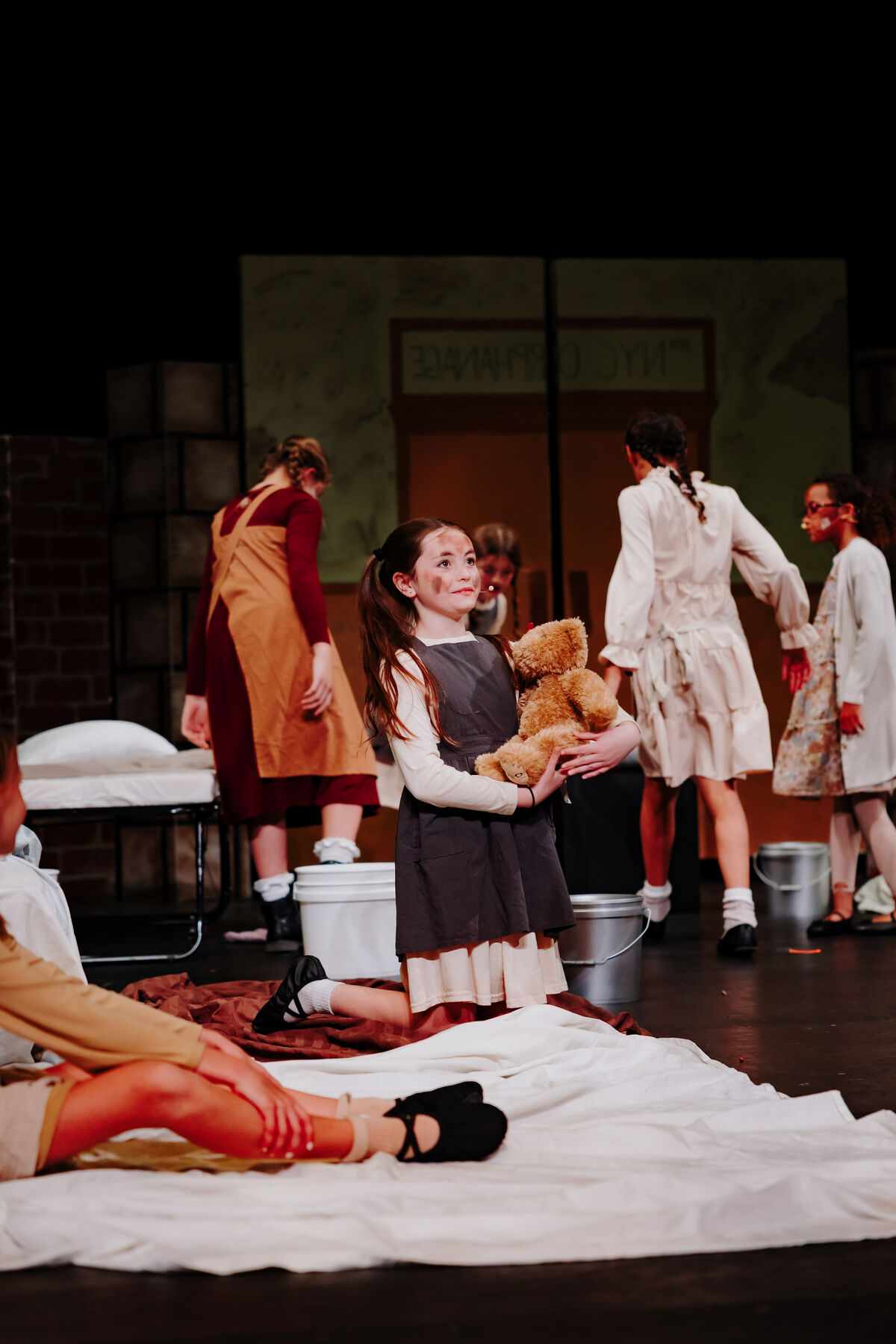 child holding a stuffed bear, amongst other children.