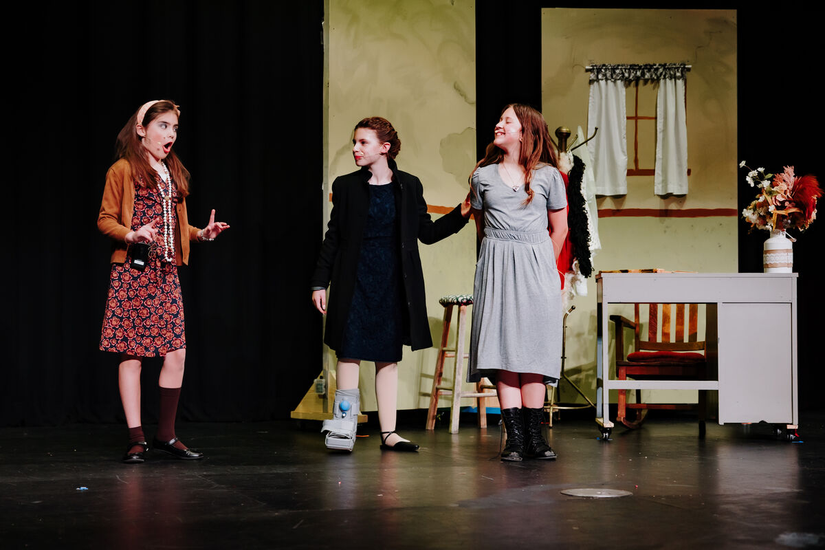 3 children standing on a stage for a performance