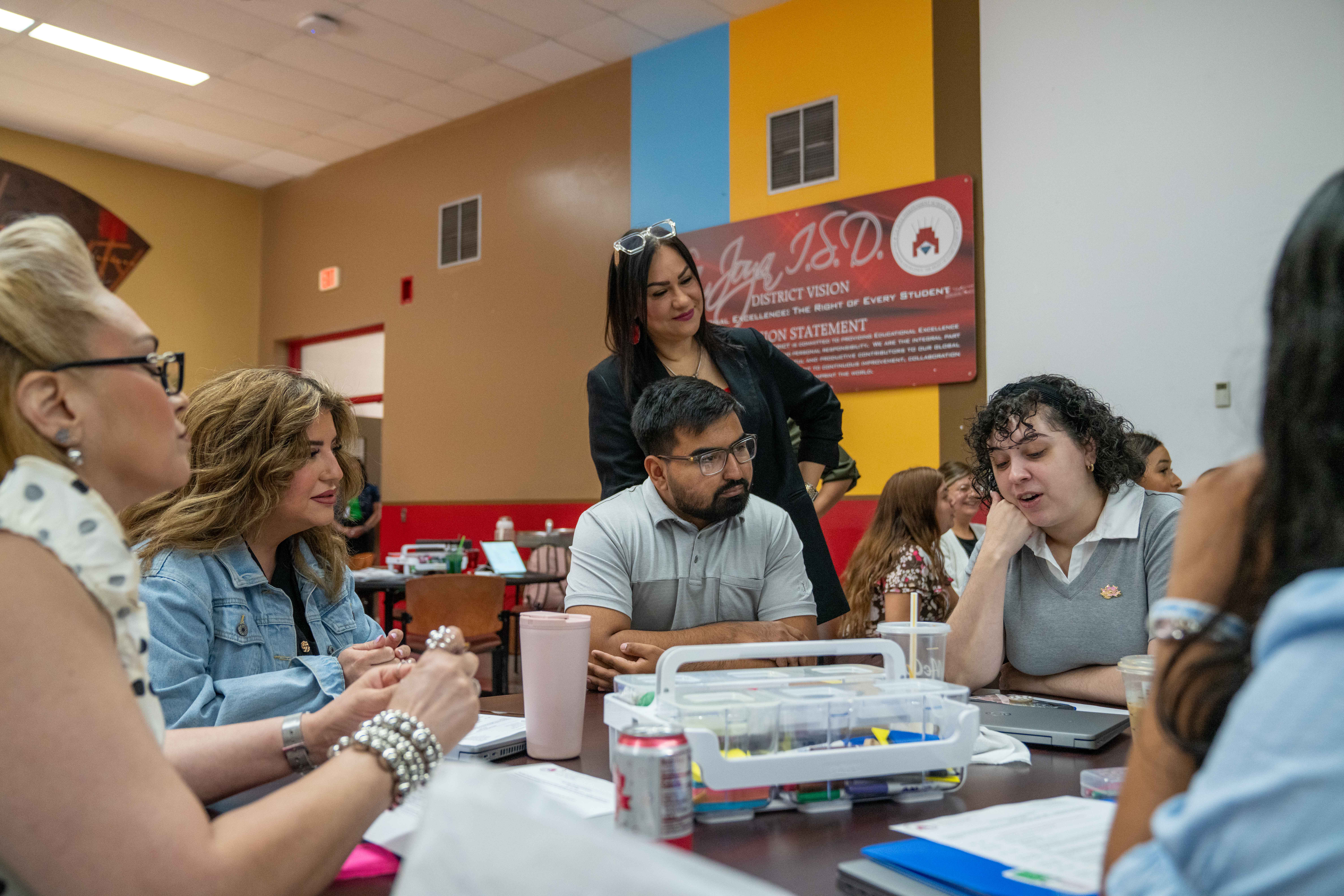A group of people are gathered around a table, engaged in a discussion.