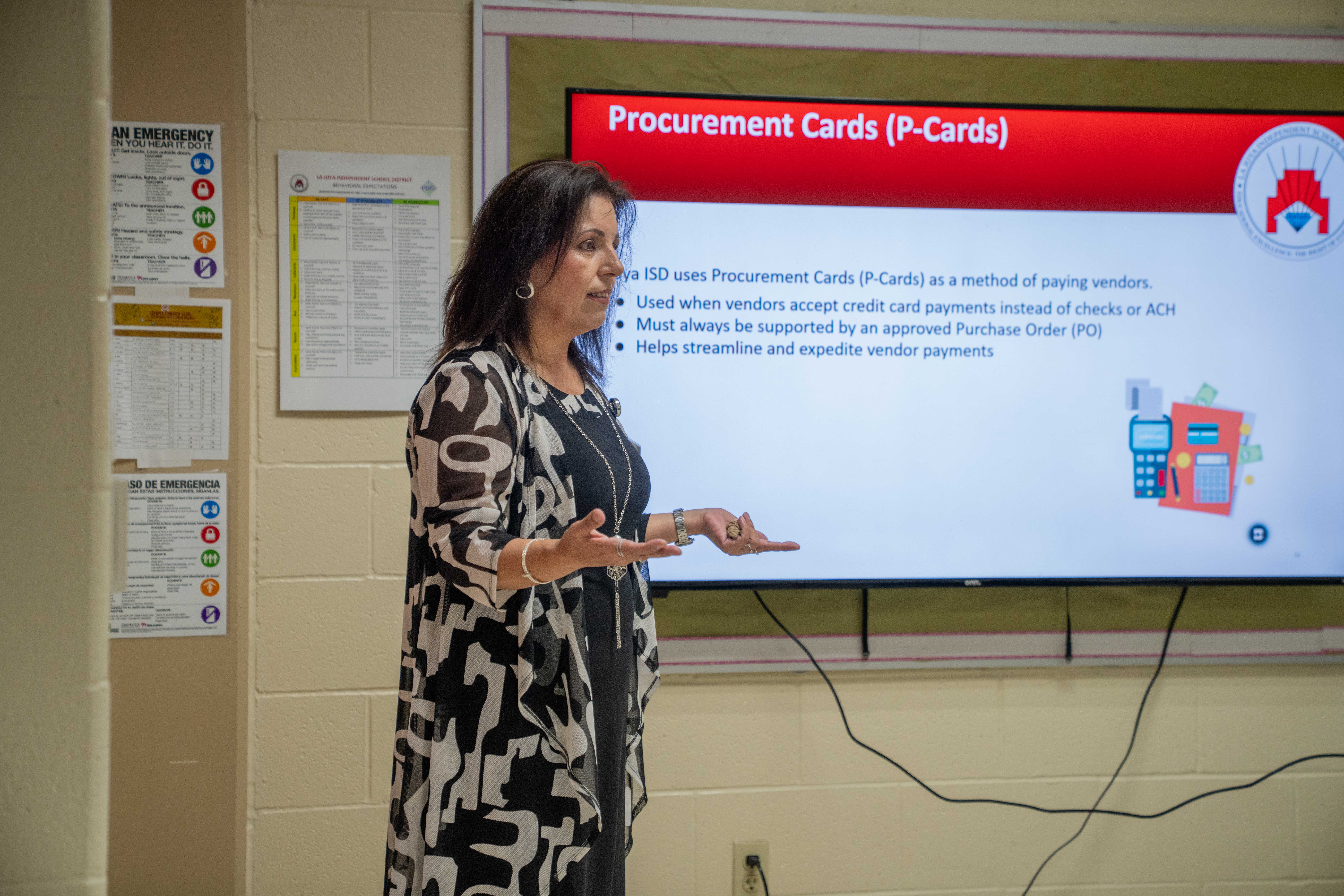 A woman presents information about Procurement Cards (P-Cards) on a large screen in a classroom.