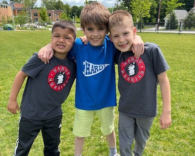 Students wearing Hardy gear pose on field.