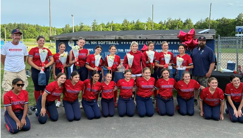 A softball team poses for a photo with coaches, holding bouquets of flowers.