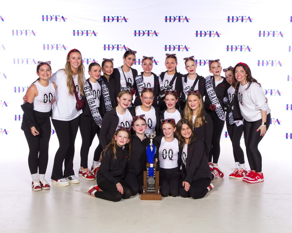 A dance team poses for a photo with a trophy, wearing matching outfits and sunglasses.