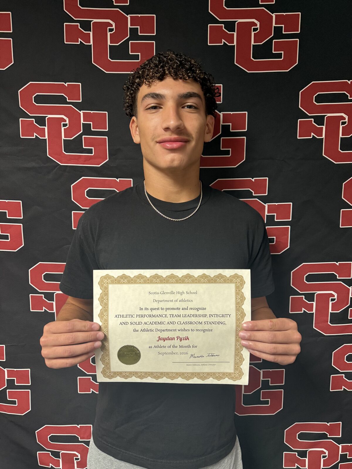 A young person proudly holds a certificate from Scotia-Glenville High School, recognizing Jaydan Pyzik as Athlete of the Month.