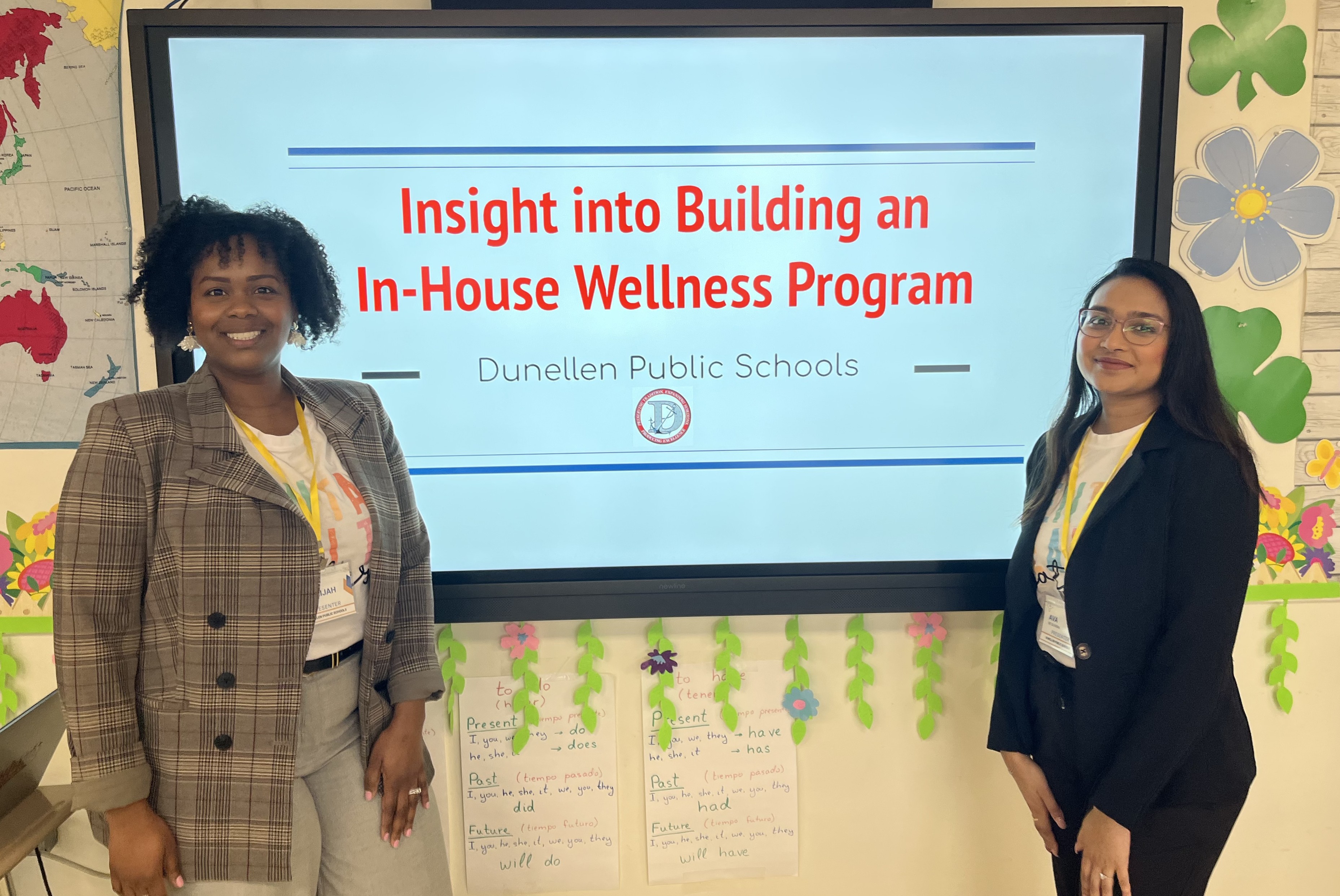 Two women stand in front of a presentation screen titled 'Insight into Building an In-House Wellness Program' for Dunellen Public Schools.
