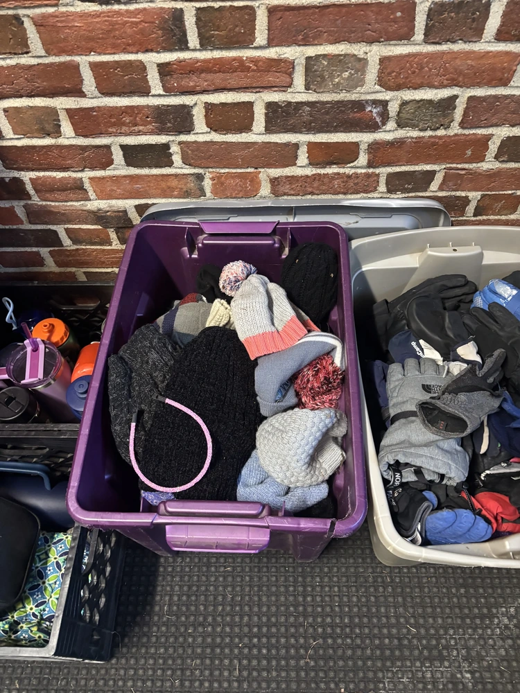 A purple bin overflowing with winter hats of various colors and textures.