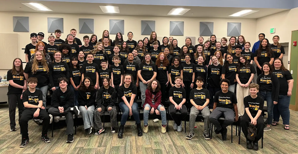 A large group of students in matching black t-shirts pose for a photo.