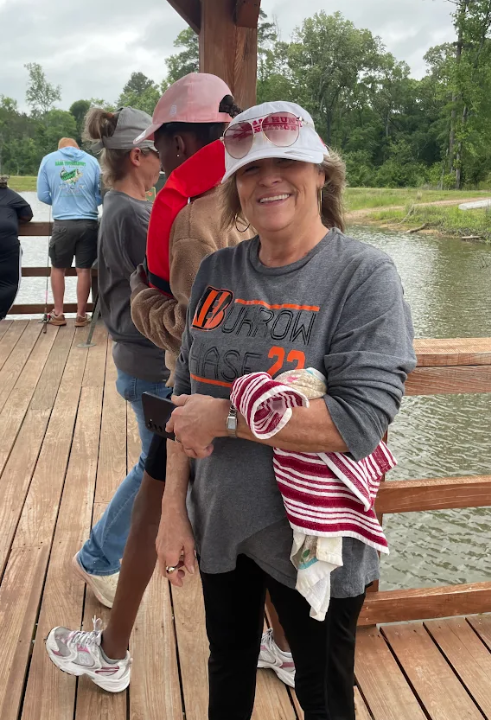 A woman in a grey t-shirt with 'BURROW CHASE 22' smiles at the camera on a wooden pier.