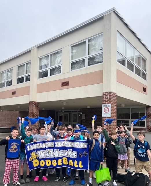 A group of students proudly hold a banner that reads 'Lancaster Elementary Wildcats Dodgeball'.
