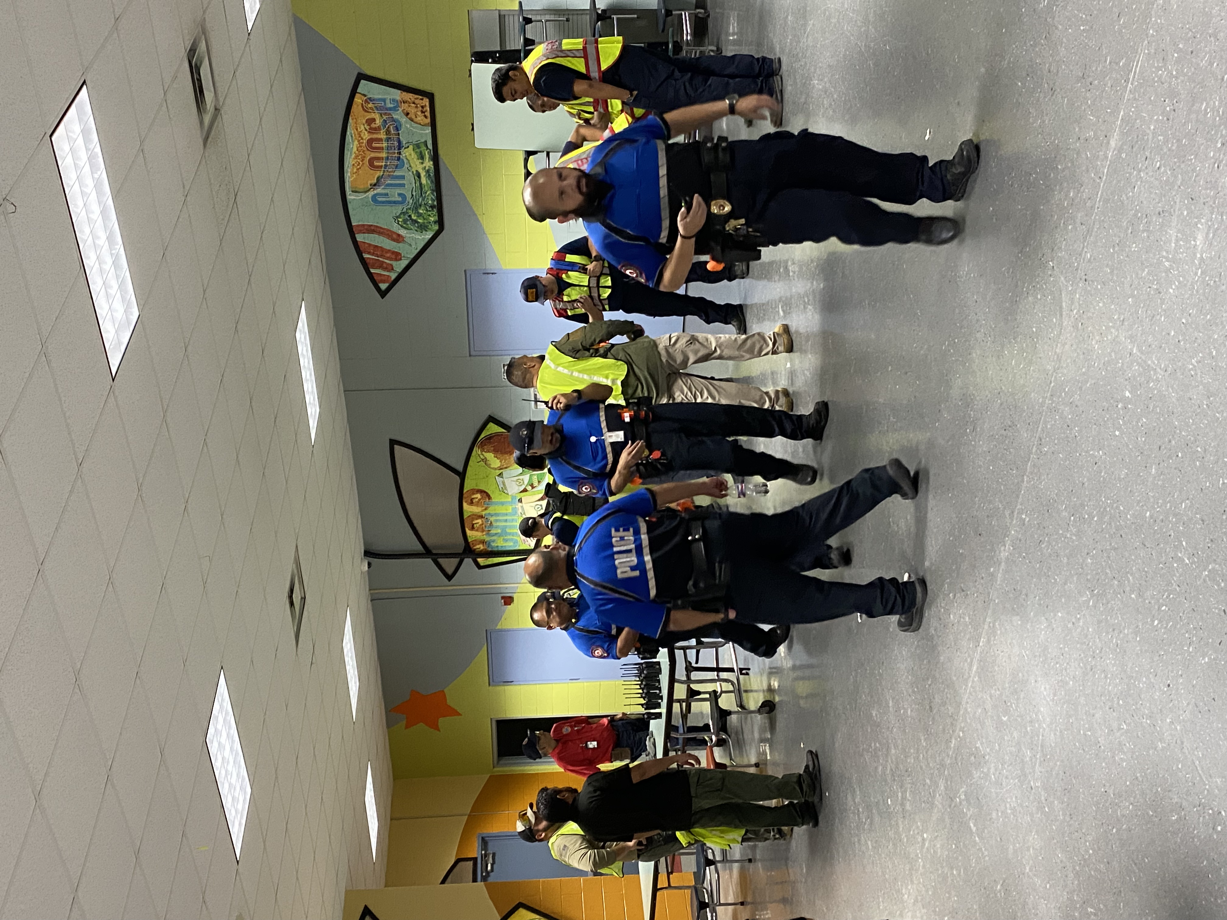 A group of security and safety personnel stand in a brightly lit indoor hallway with colorful wall art.