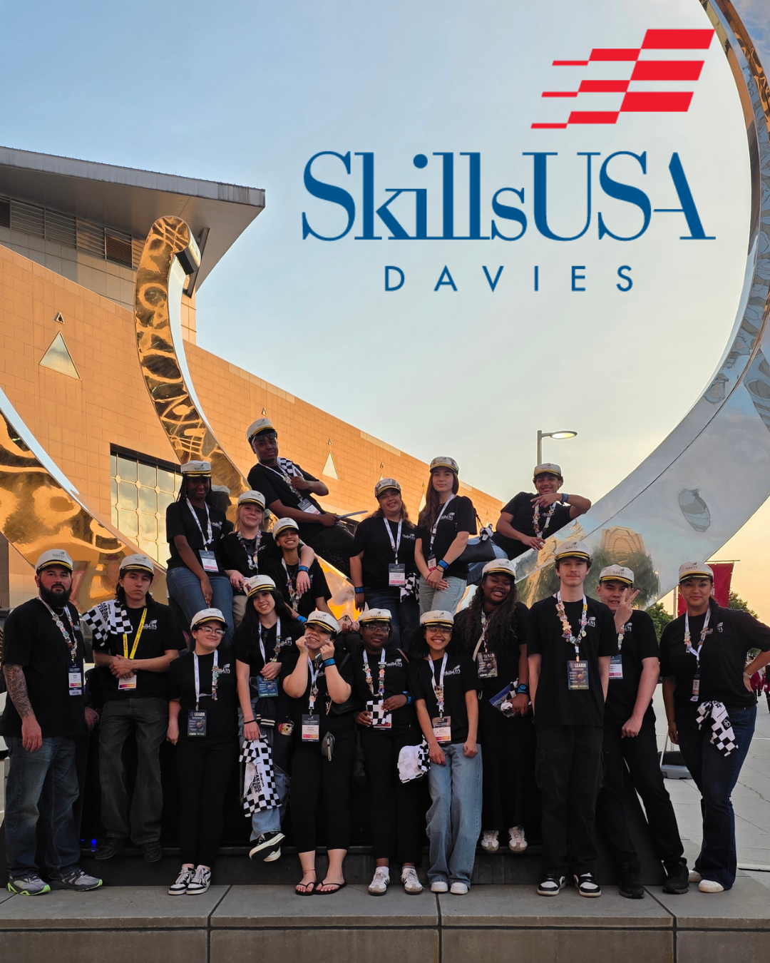 A group of students in black shirts and hats pose in front of a large, abstract sculpture with the SkillsUSA Davies logo.